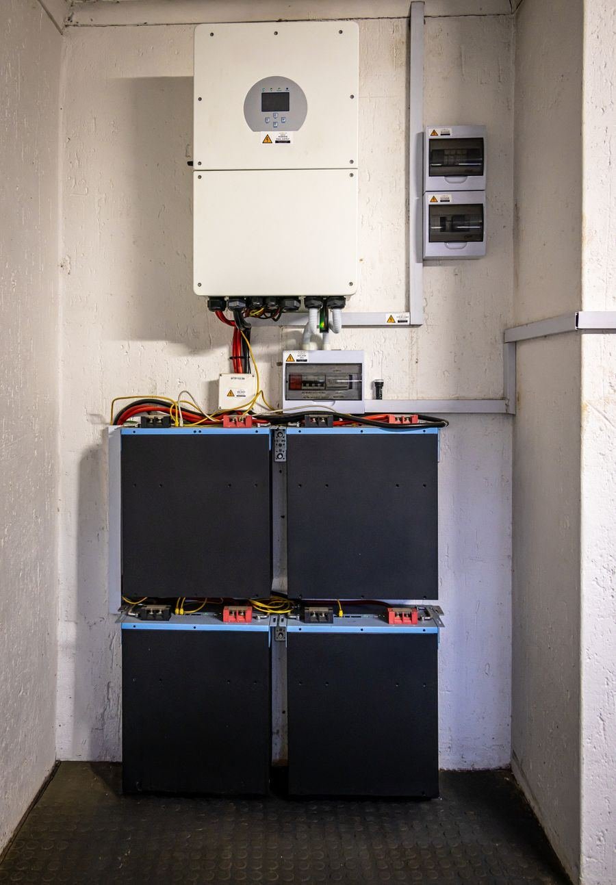 A wall mounted hybrid inverter above a stack of battery storage modules.